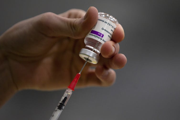 A hand draws up a vial of the AstraZeneca vaccine.