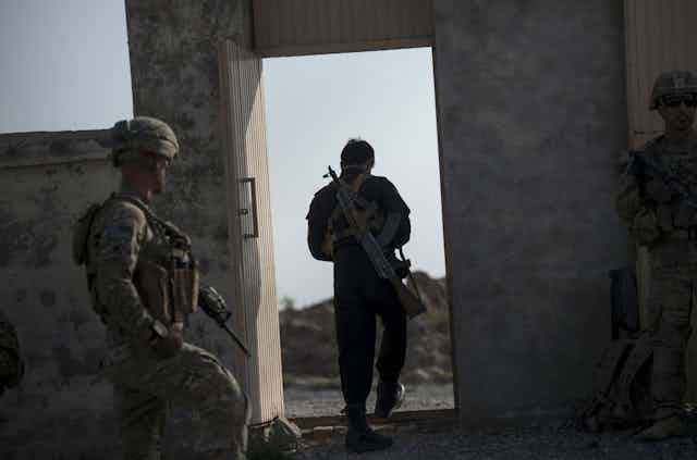Un policía afgano y soldados estadounidenses salen de una escuela