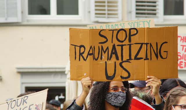 A protestor holds sign that says 'stop traumatizing us.'