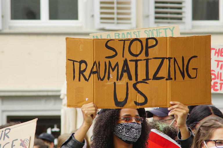 A protestor holds sign that says 'stop traumatizing us.'