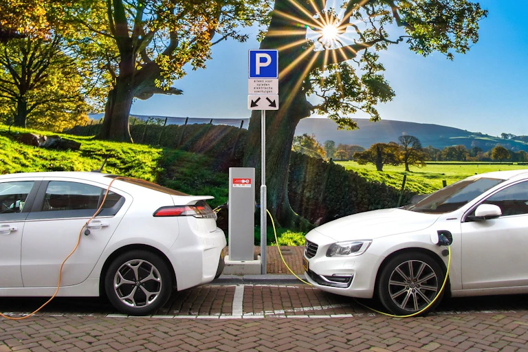 Two white electric cars charge in the sunshine