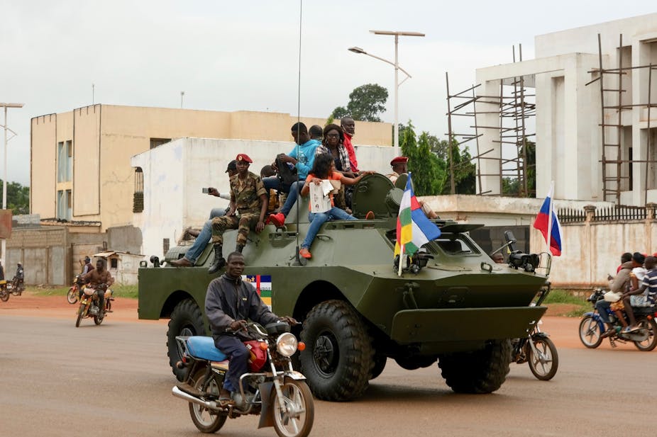 Civilians get a ride atop an armoured personnel carrier 