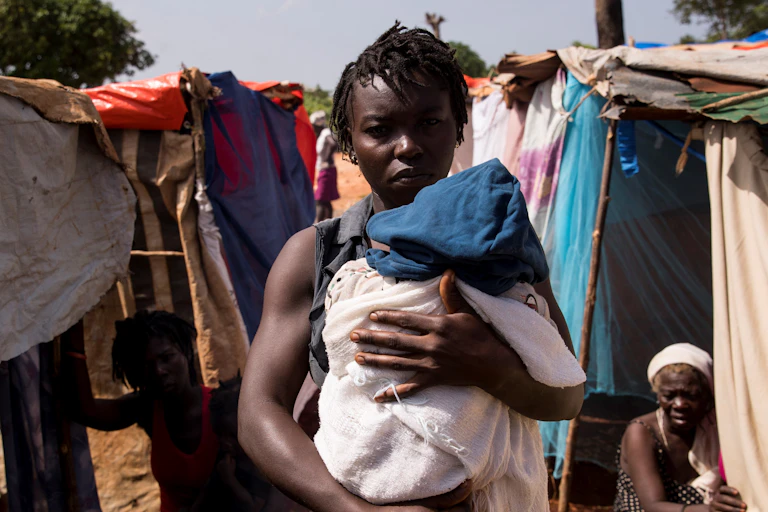 A woman carries a baby after the Haitian earthquake