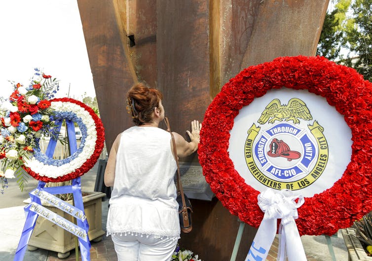 Maria Antonia Fernandez-Lopez touches an original steel beam from one of the twin towers of the World Trade Center to commemorate the 14th anniversary of 9/11 at the Frank Hotchkin Memorial Training Center in Los Angeles.