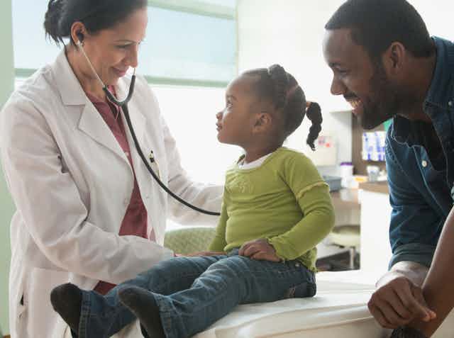 Doctor examining child in exam room with parent.