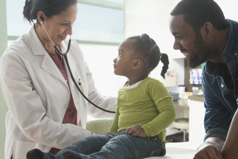 Doctor examining child in exam room with parent.