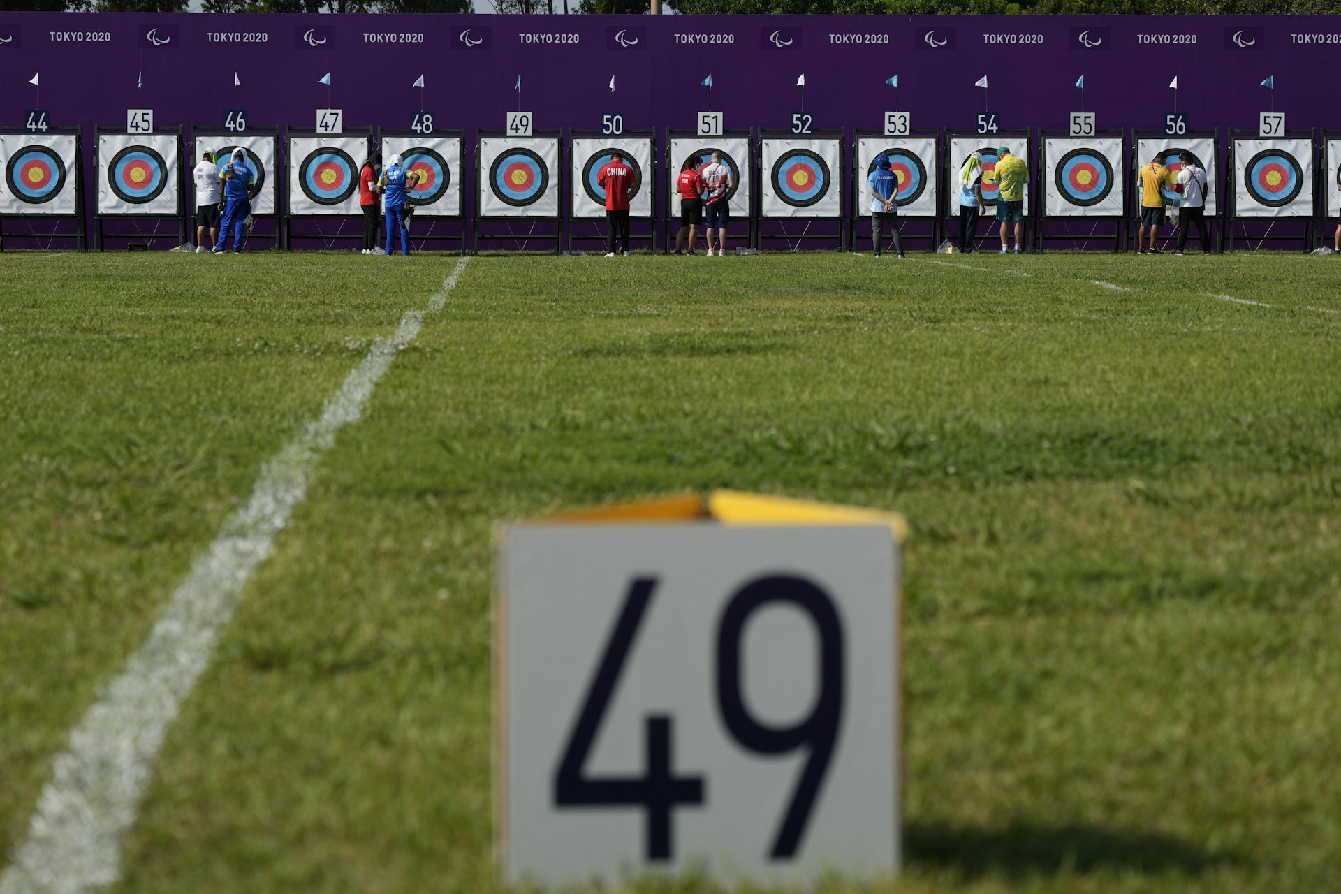 Athletes inspect their archery targets in the distance