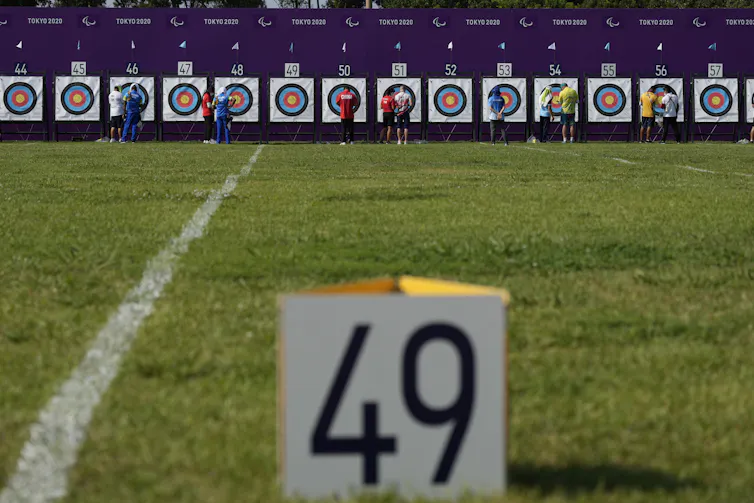 Athletes inspect their archery targets in the distance