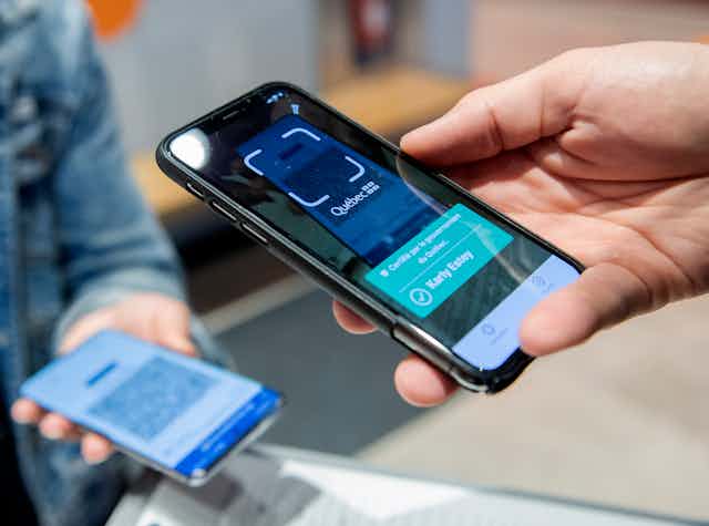 un téléphone cellulaire tenu dans une main, en train de scanner un autre cellulaire