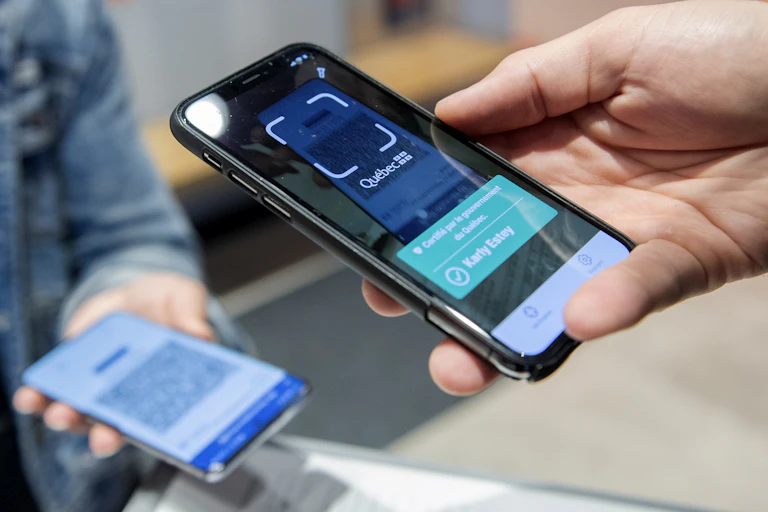 un téléphone cellulaire tenu dans une main, en train de scanner un autre cellulaire