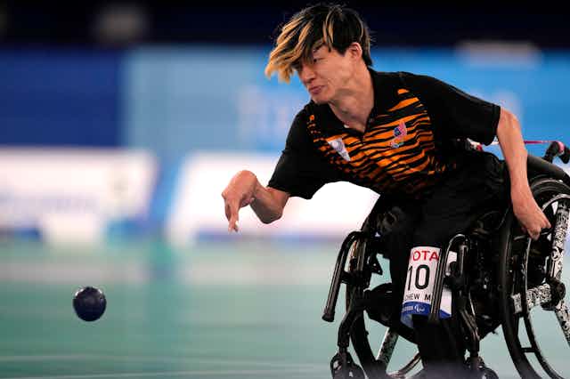 An athlete in a wheelchair throws a boccia ball