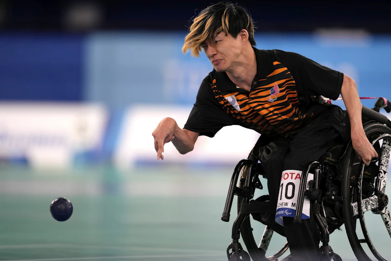 An athlete in a wheelchair throws a boccia ball