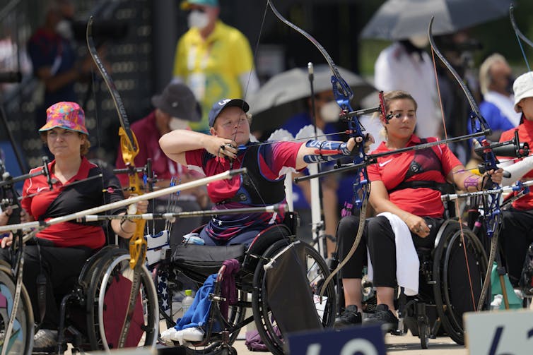 Wheelchair para-archery athletes pulling the string back on their bows