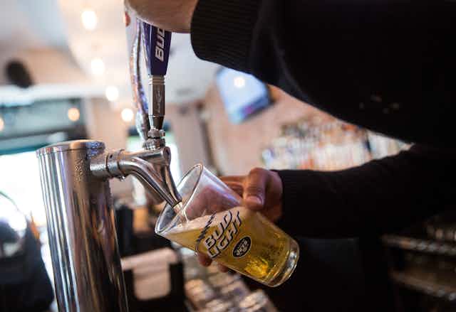 A bartender pours a beer into a Bud Light glass