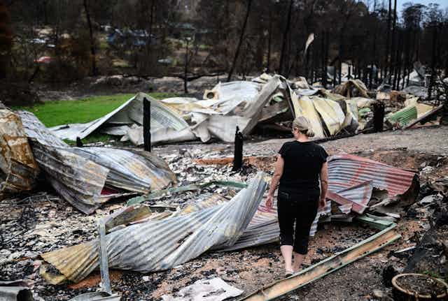 A woman observes wreckage from a bushfire.