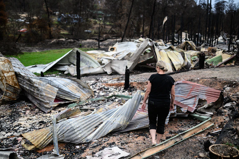 A woman observes wreckage from a bushfire.