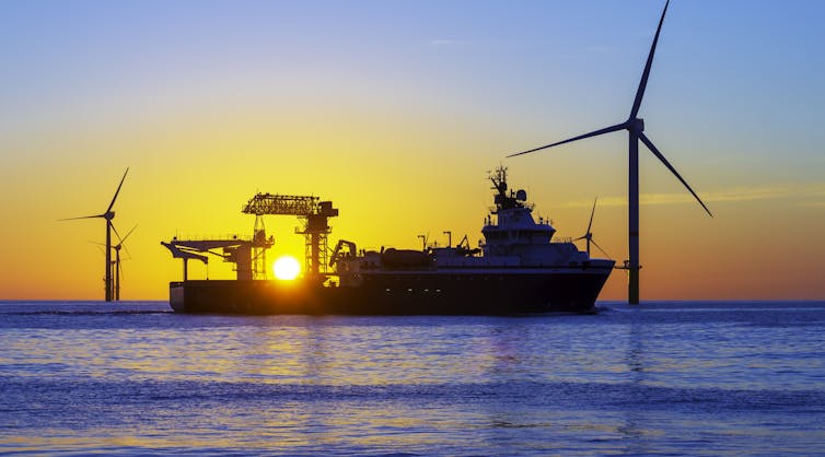 A ship outside turbines at sunset
