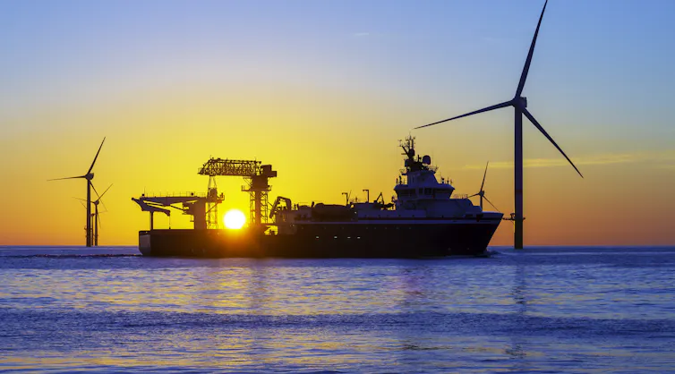A ship outside turbines at sunset