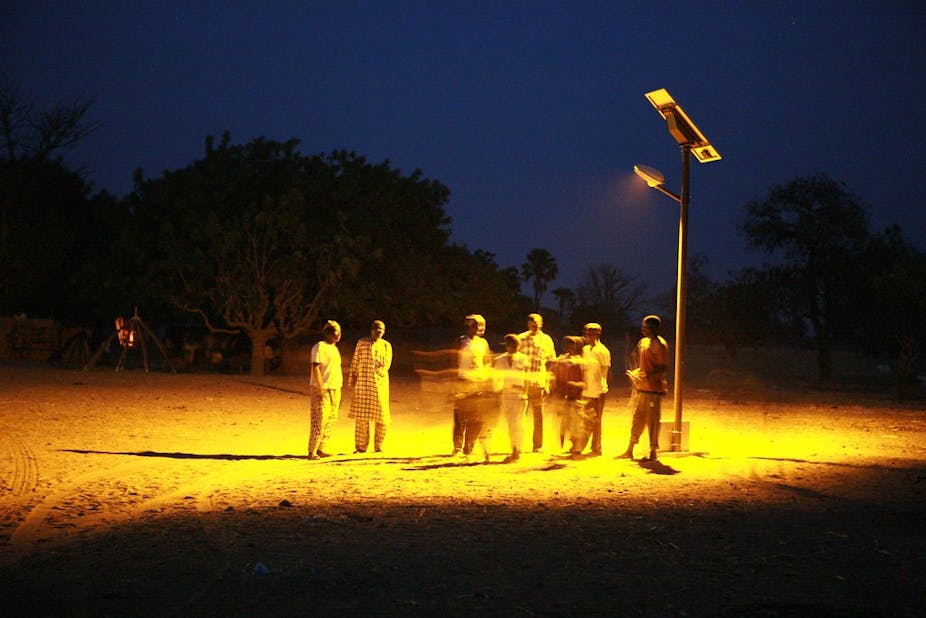People standing under a solar lamp.