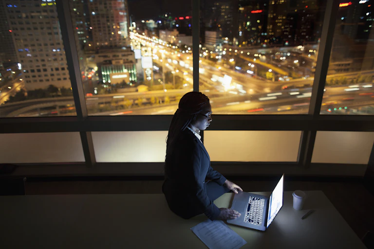 Young woman sitting on table while viewing laptop