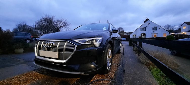 An electric car charges outside a home