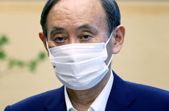 Head and sloulders picture of the Japanese prime minister, Yoshihide Suga, wearing a COVID mask.