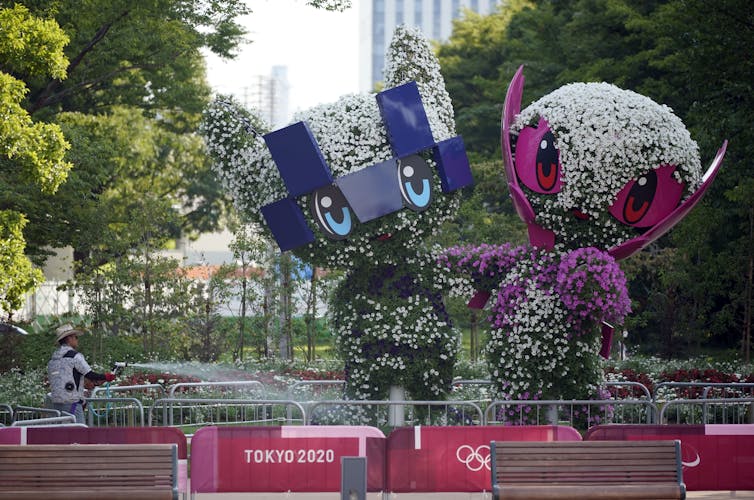 jardineiro rega árvores cortadas no formato dos mascotes dos Jogos Olímpicos de Tóquio 2020 em Tóquio, julho de 2021.
