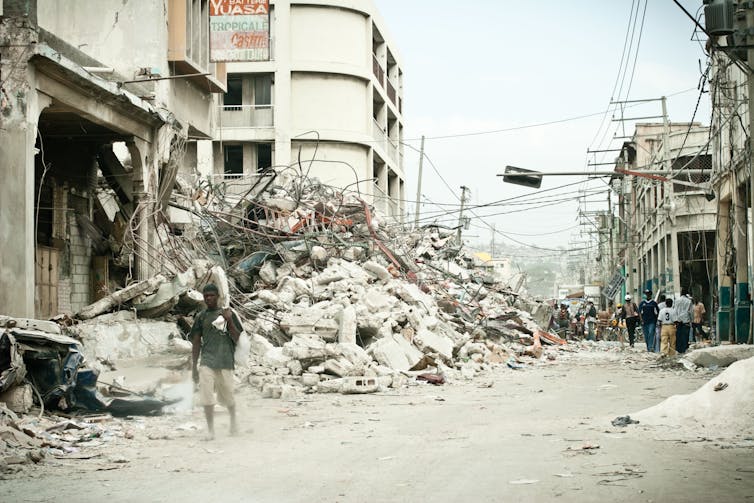 Man walks down earthquake-shattered street.