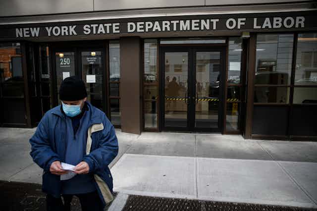 A man wearing a mask walks away from the New York State Department of Labor.