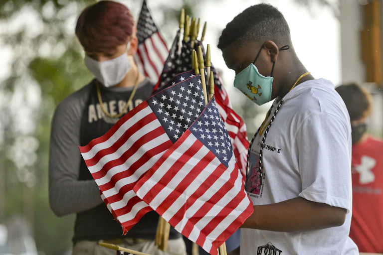 Two high school boys hold a bunch of small US flags