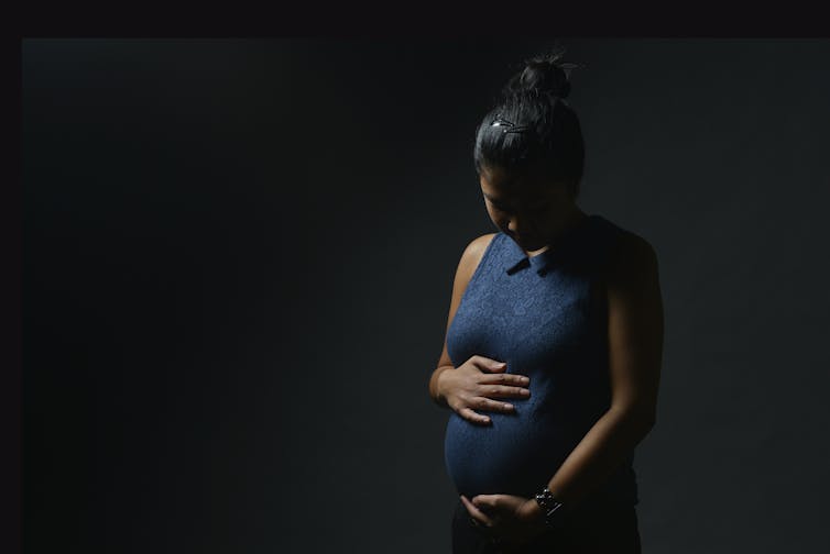 Pregnant woman cradling her belly.