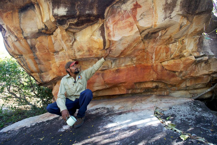 A man sits beside rock art in the North Kimberley.