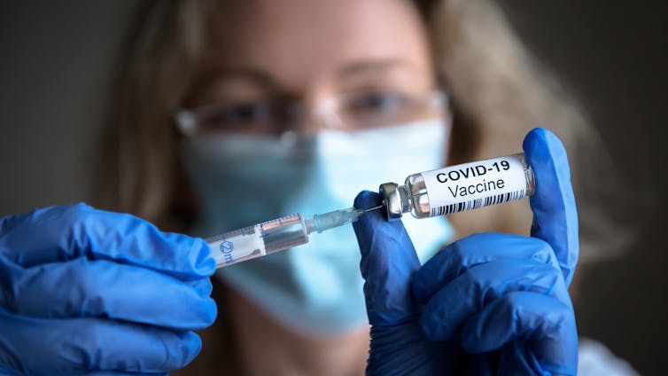Woman holding COVID vaccine vial.