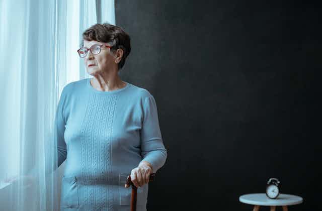 Elderly woman looking out a window.