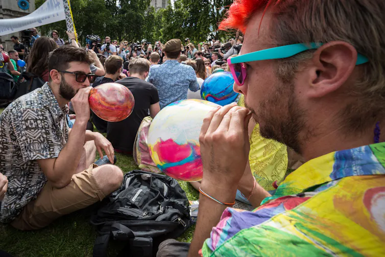 People inhaling nitrous oxide from a balloon