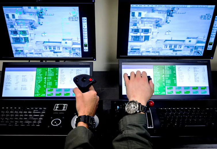 Hands of student pilots shown operating a joystick device to control a drone, with controls shown on a screen
