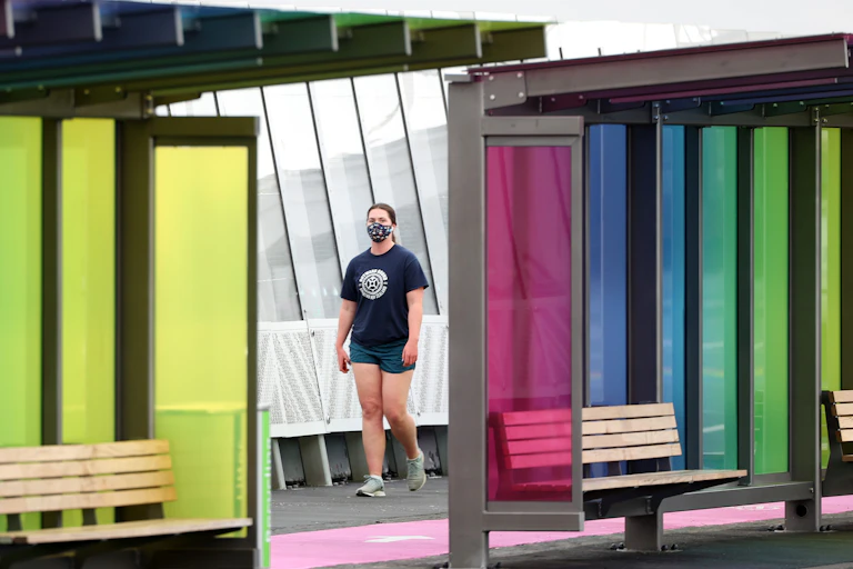 Masked woman walking past bus shelters