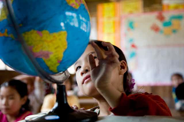 A school girl looks at countries on a globe