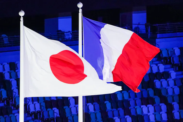 The French and Japanese flags fly during the closing ceremony of the Tokyo 2020 Games