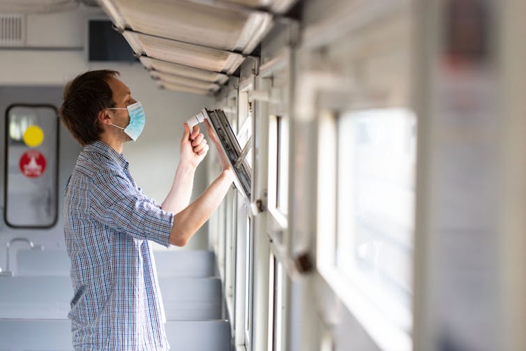Un homme ouvre la fenêtre dans un train pour permettre d’aérer
