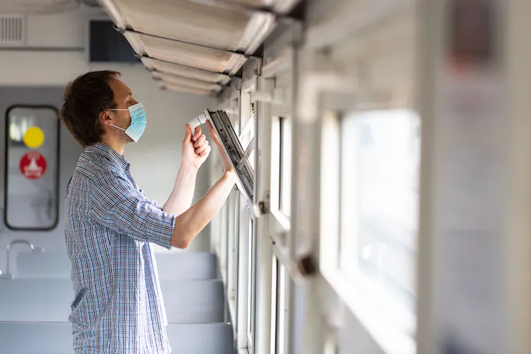 Un homme ouvre la fenêtre dans un train pour permettre d’aérer