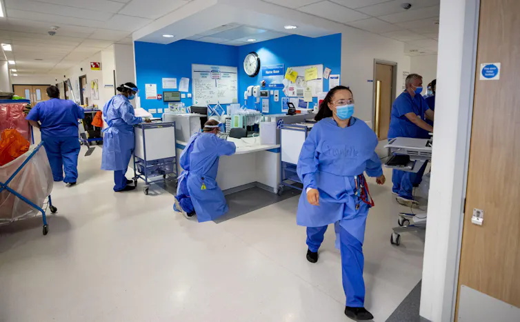 Nursing staff bustle about a busy NHS ward