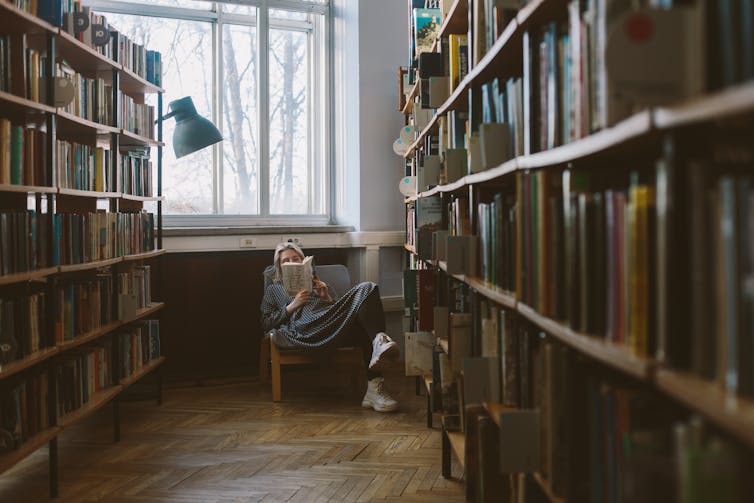 Woman sitting in book store reading books.