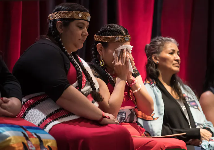 An Indigenous woman wipes away tears.