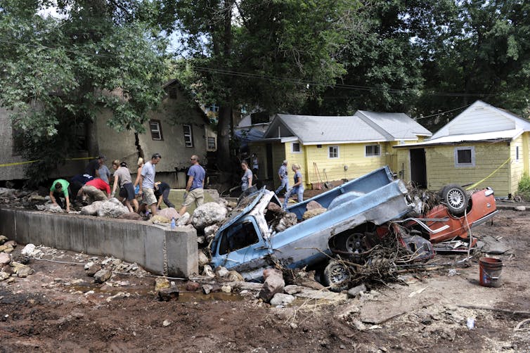 People search through damaged homes and vehicles, including an old truck nose down in the foundation of a home that's no longer there.