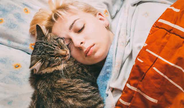 A sleeping teen next to a cat.