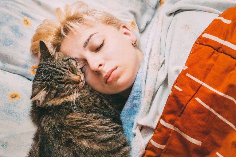 A sleeping teen next to a cat.