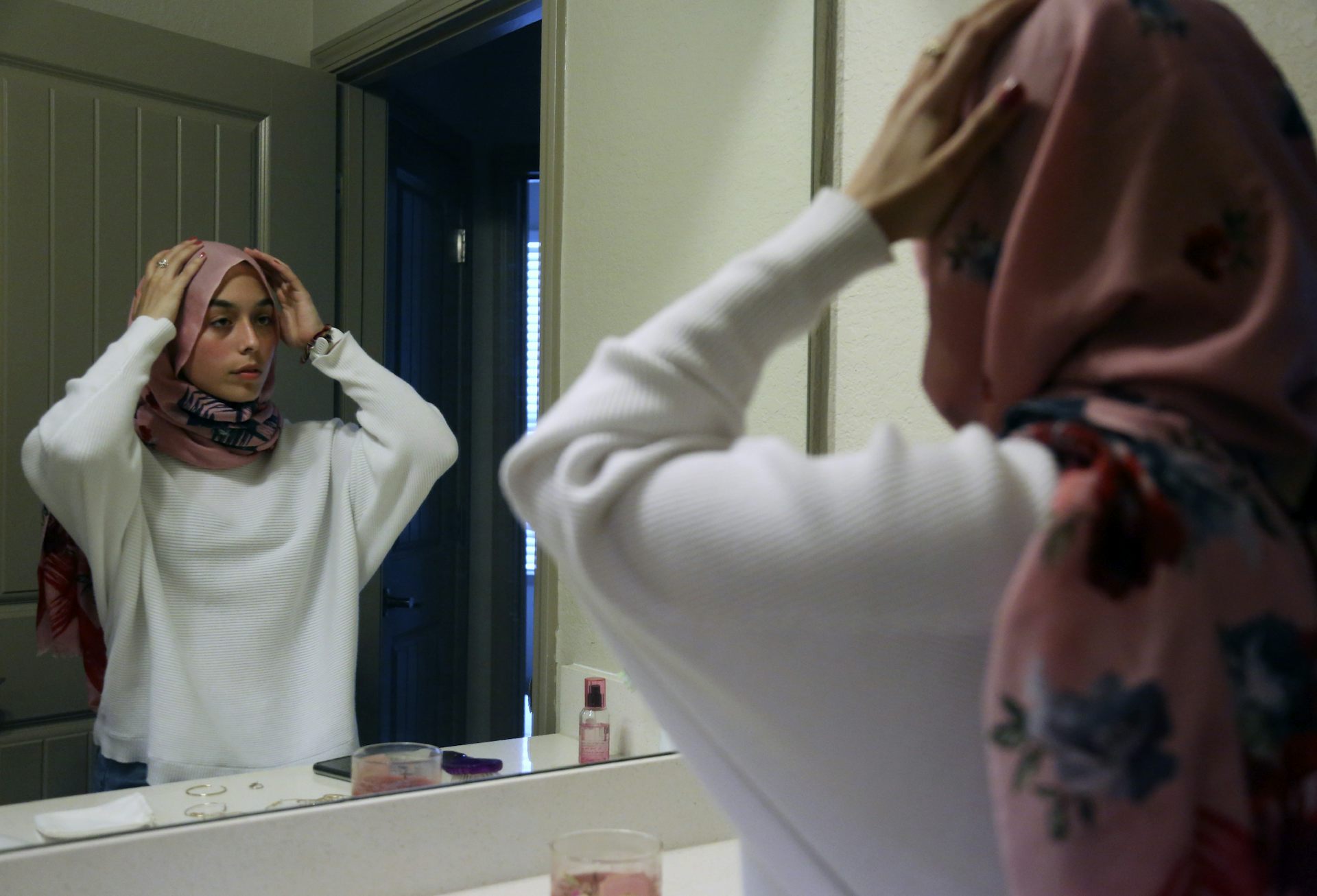 Teenager adjusts her hijab in mirror