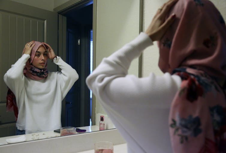 Adolescente ajeitando seu hijab no espelho