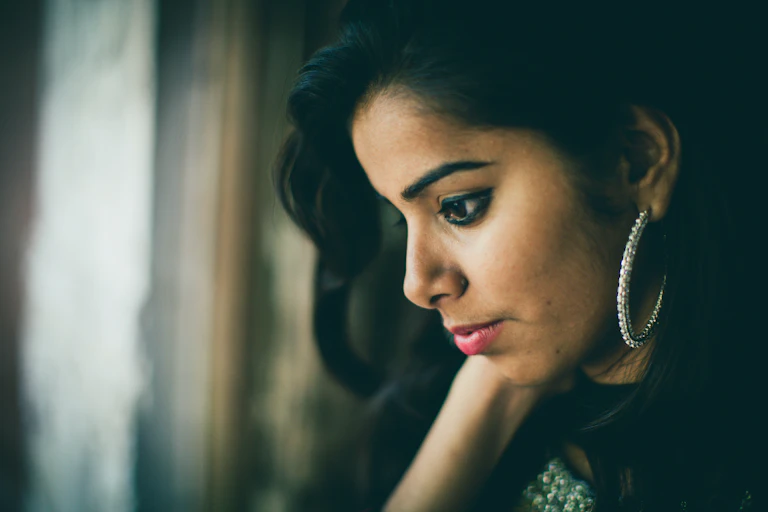 Profile of person wearing large hopped earring looking down.